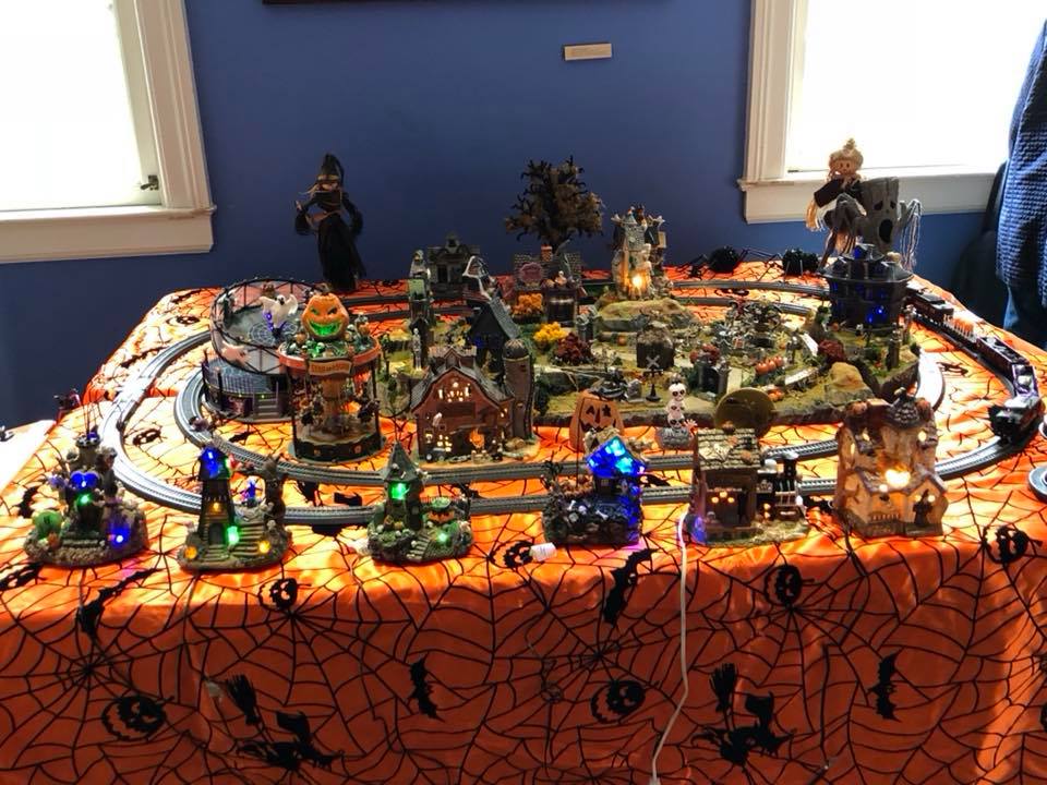 Halloween-themed model train layout with spooky village decorations and glowing lights