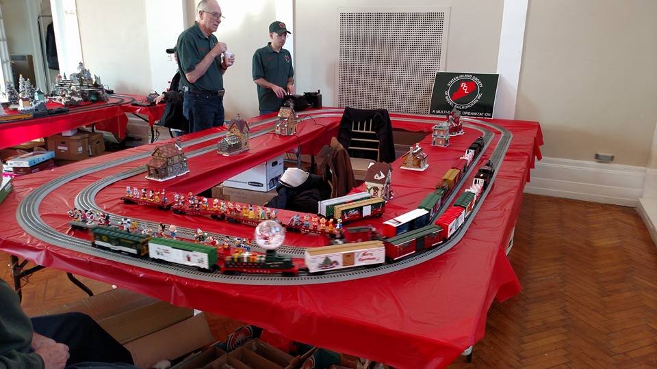 SISMR members operating a holiday train layout with the club sign visible